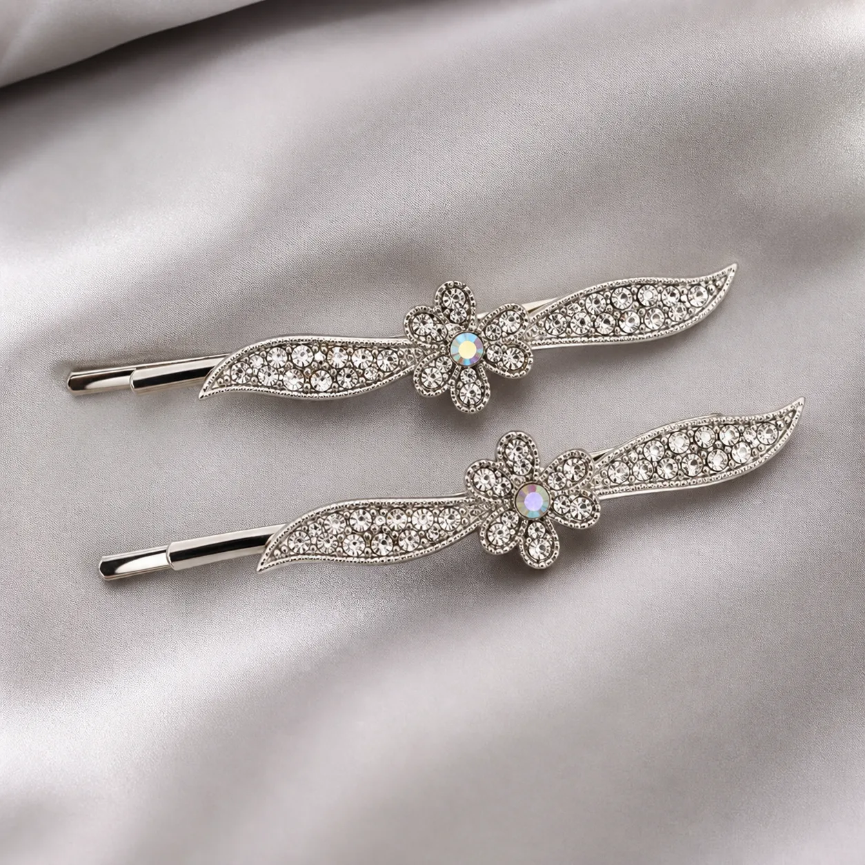 Conjunto de 2 Ganchos Prateados com Folhas e Strass Ganchos prateados com folhas alongadas e flor central sobre cetim