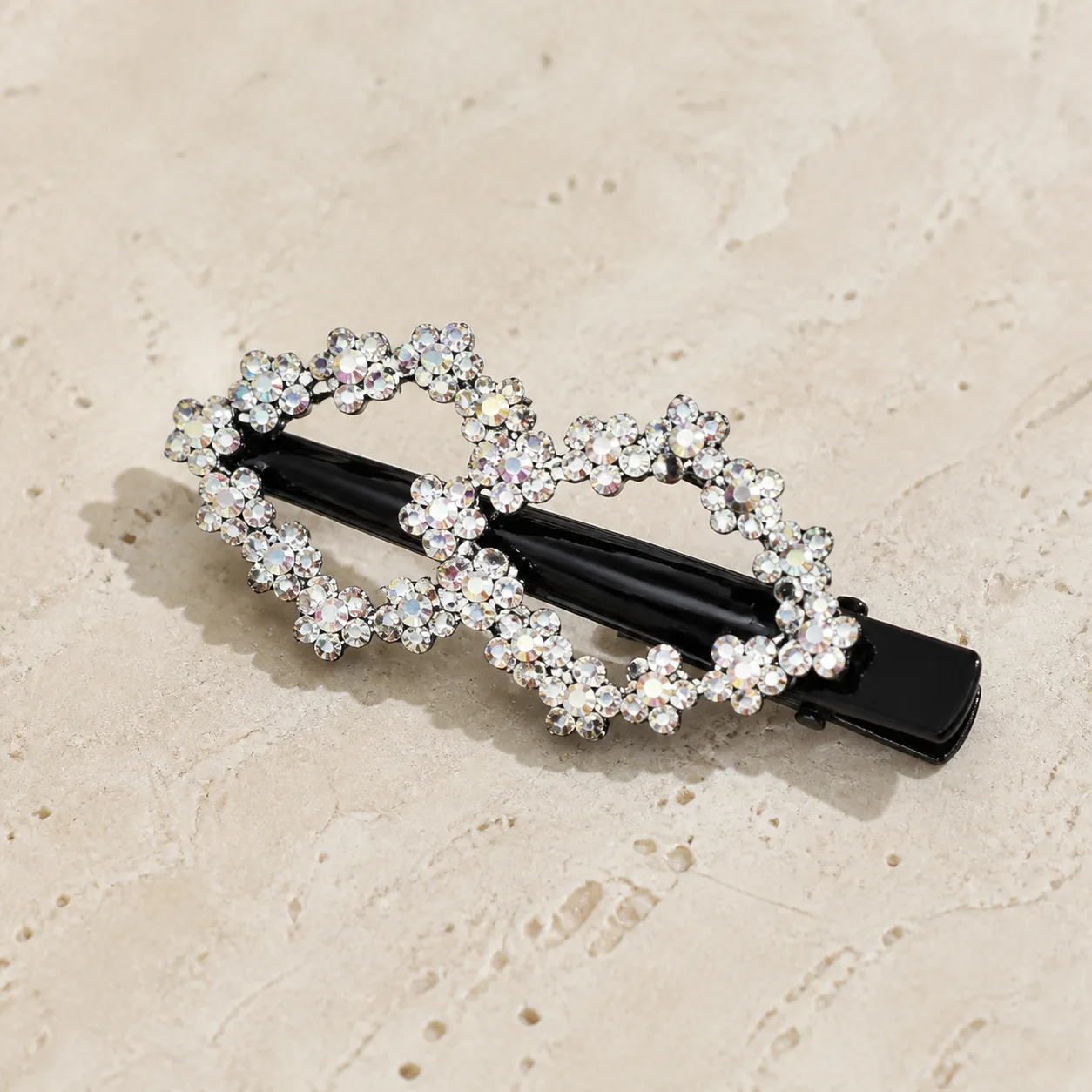 Gancho Preto com Flores de Strass Branco Gancho de cabelo preto com flores de strass sobre pedra bege