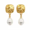 Brincos dourados martelados com pérolas em fundo branco