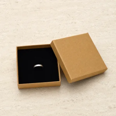 Caixa de joias kraft 9x9 cm aberta sobre pedra clara