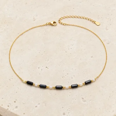 colar dourado preto com pérolas e amuletos, A — Cinco Barras Negras e Pérolas, em pedra clara de tom quente, referencia 85182-02