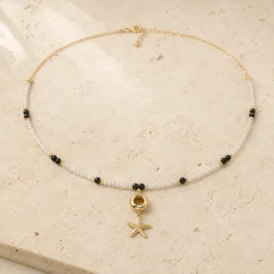 colar dourado preto com pérolas e amuletos, J — Pérolas, Aro e Estrela-do-Mar, em pedra clara de tom quente, referencia 85182-02