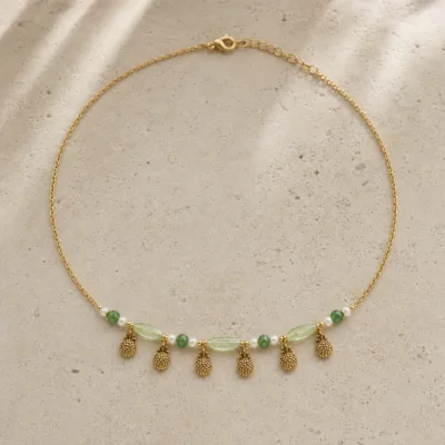 colar dourado verde com pérolas e amuletos, F — Seis Pinhas Douradas, em pedra clara de tom quente, referencia 85182-05