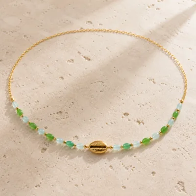 colar dourado verde com pérolas e amuletos, H — Búzio Dourado com Contas Verdes, em pedra clara de tom quente, referencia 85182-05
