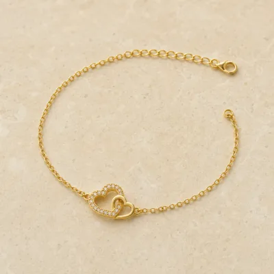 pulseira com corações entrelaçados dourada em pedra clara de tom quente, referência 85203-09