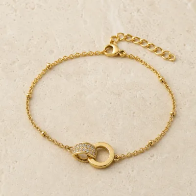 pulseira com dois círculos entrelaçados dourado em pedra clara de tom quente, referência 85204-17