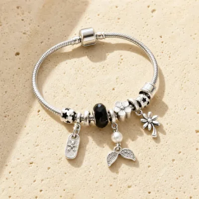 Pulseira prateada com berloques pretos, uma pulseira sobre pedra quente
