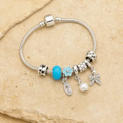 Pulseira prateada com berloques azuis, uma pulseira sobre pedra quente