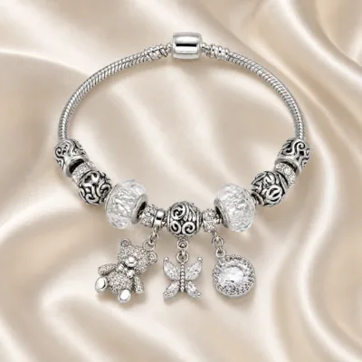 pulseira prateada com urso e borboleta em cetim marfim, referencia 85327-6