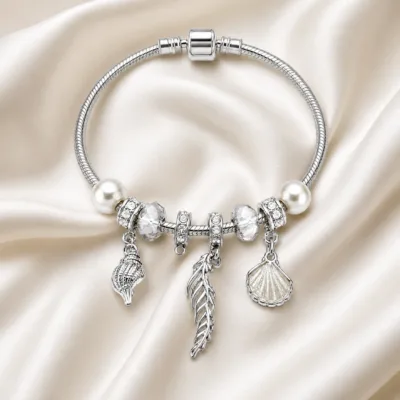 pulseira prateada transparente com conchas em cetim marfim, referencia 85328-1