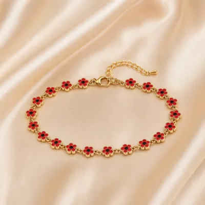 Pulseira dourada de flores vermelhas com centros pretos, uma pulseira, sobre cetim bege