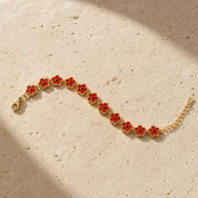 Pulseira dourada de flores vermelhas com centros pretos, uma pulseira, sobre pedra quente