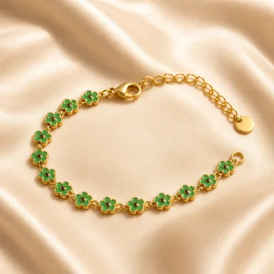 Pulseira dourada de flores verdes sobre cetim bege