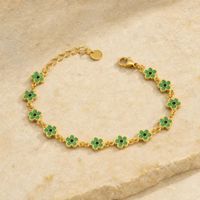 Pulseira dourada de flores verdes sobre pedra quente