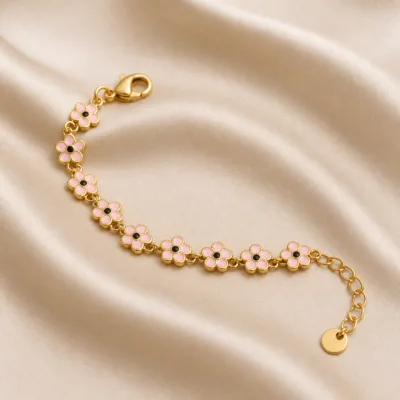 Pulseira dourada de flores rosa com centros pretos, uma pulseira, sobre cetim bege