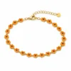 Pulseira dourada de flores laranja com centros pretos, uma pulseira, vista em fundo branco