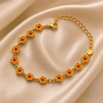 Pulseira dourada de flores laranja com centros pretos, uma pulseira, sobre cetim bege