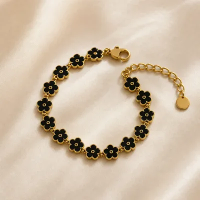 Pulseira dourada de flores pretas, uma pulseira, sobre cetim bege