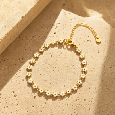 Pulseira dourada de flores brancas, uma pulseira sobre pedra quente