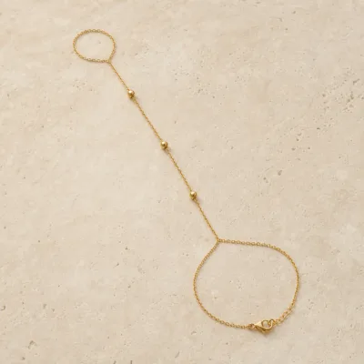 pulseira de mão dourada com três contas em pedra clara de tom quente, referência 85473-2
