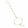 pulseira de mão dourada com seis cristais e contas em fundo branco, referência 85476-1