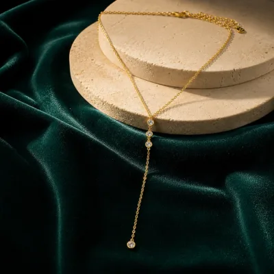 Colar dourado em Y apresentado sobre veludo verde