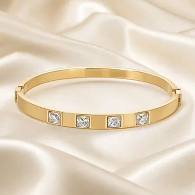 Pulseira dourada rígida com quatro cristais quadrados em cetim marfim