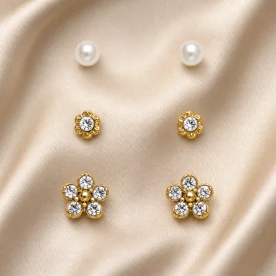 Conjunto de 3 pares de brincos dourados florais sobre cetim bege claro