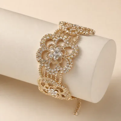 Pulseira larga dourada floral apresentada sobre suporte neutro