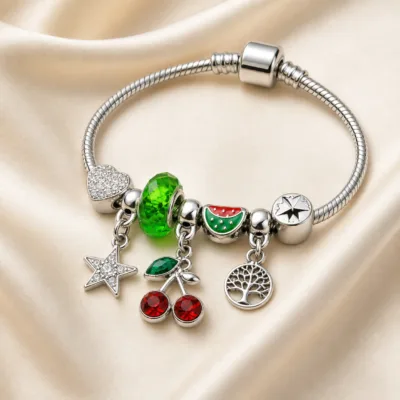 Pulseira Prateada de Aço com Berloques de Cereja Verde sobre cetim bege claro