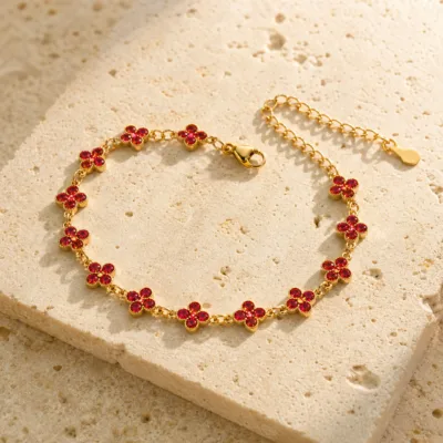Pulseira Dourada com Flores de Cristal Vermelho sobre pedra quente