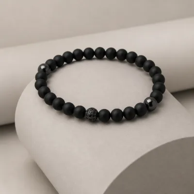 Pulseira preta apresentada num suporte neutro