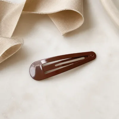 Gancho de cabelo castanho sobre tecido bege