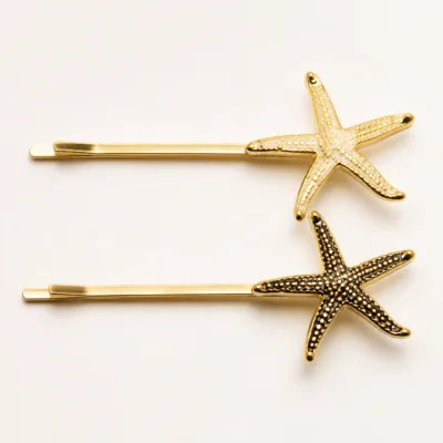Conjunto de dois ganchos dourados com estrelas-do-mar escura e marfim