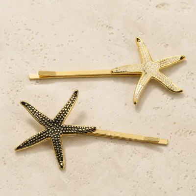 Ganchos dourados com estrelas-do-mar texturadas sobre pedra clara