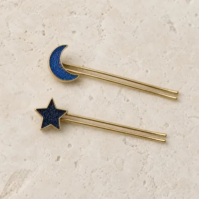 Ganchos dourados de duas pontas com lua e estrela em detalhe