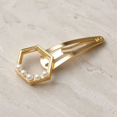 Detalhe do motivo hexagonal e das pérolas no gancho dourado