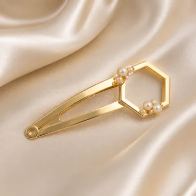 Gancho dourado hexagonal com pérolas sobre cetim