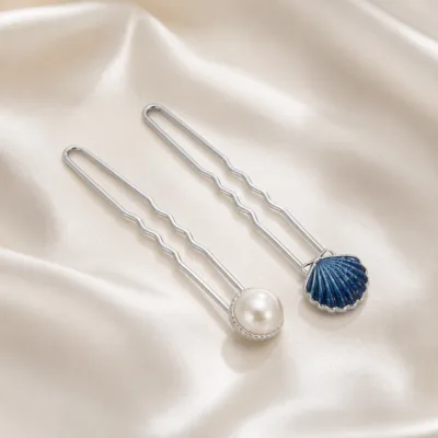 Conjunto de ganchos com pérola marfim e concha azul sobre cetim