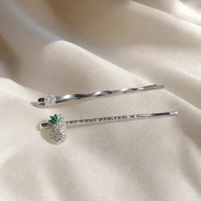 Conjunto de ganchos prateados com ananás e cristal sobre cetim