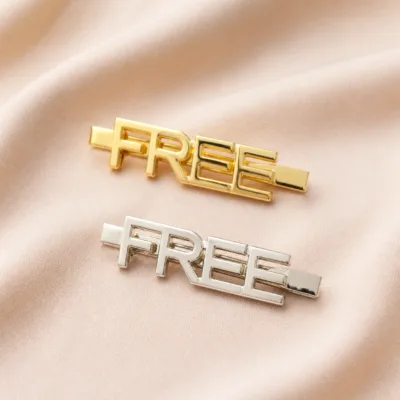 Ganchos FREE dourado e prateado sobre tecido bege