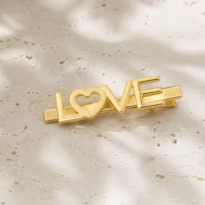 Gancho de cabelo LOVE com coração em acabamento dourado