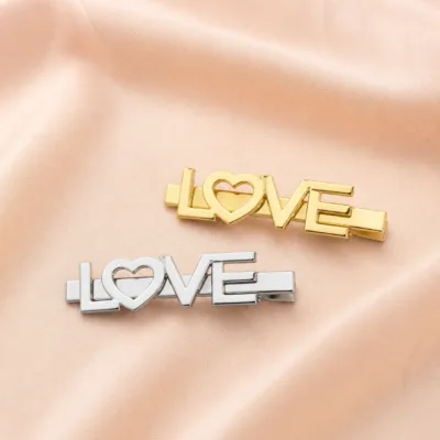 Ganchos LOVE dourado e prateado sobre tecido bege