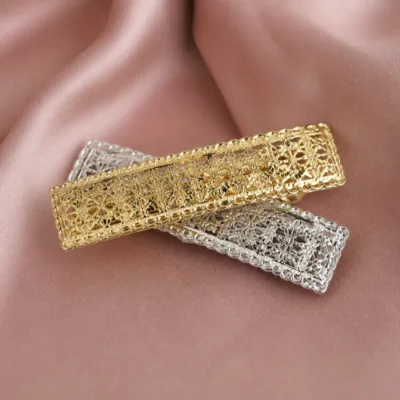 Ganchos rendilhados dourado e prateado sobre tecido rosa