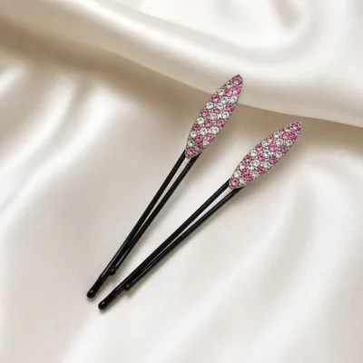 Dois ganchos pretos com strass rosa e transparente sobre cetim