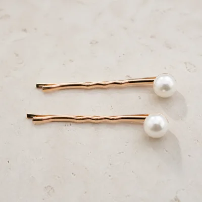 Detalhe dos ganchos ondulados rosa-dourado com pérolas grandes