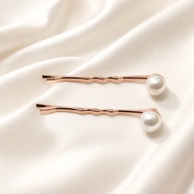 Par de ganchos rosa-dourado com pérolas sobre seda marfim