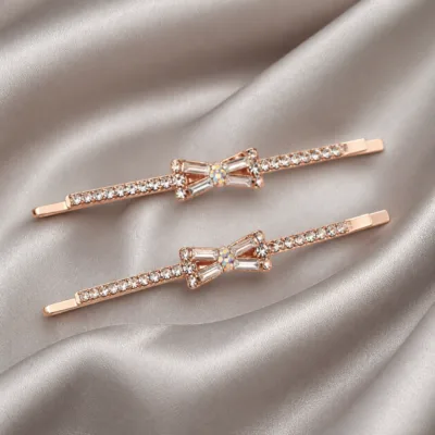 Ganchos rosa-dourado com cristais transparentes sobre cetim