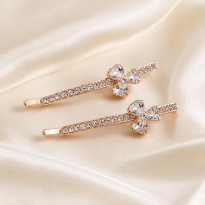 Dois ganchos rosa dourado com flores transparentes sobre cetim