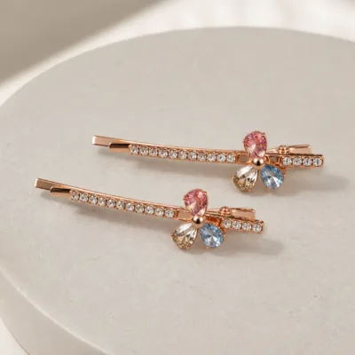 Dois ganchos rosa dourado com cristais multicolor em vista lateral